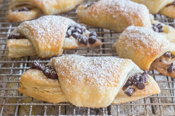 Baked crescents dusted with powdered sugar on a wire rack.